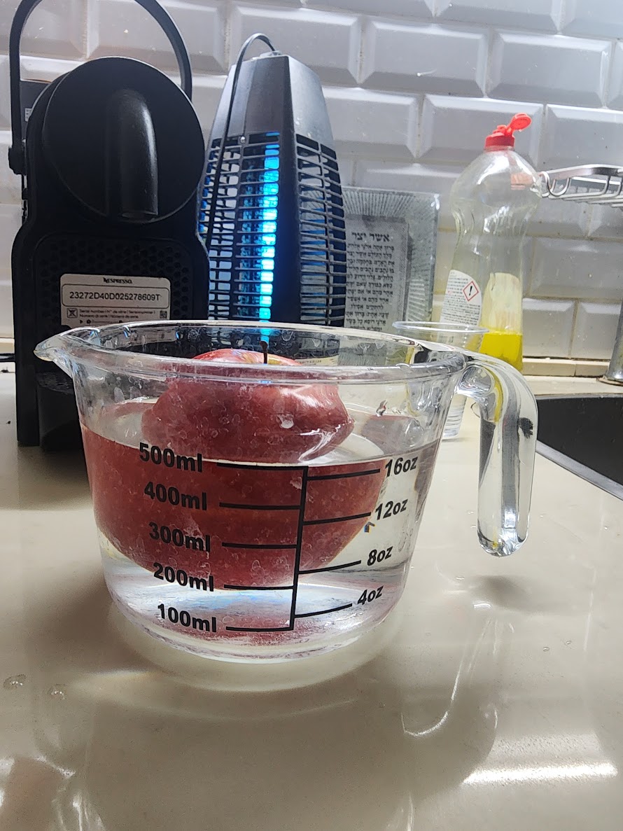 Apple submerged in a measuring cup